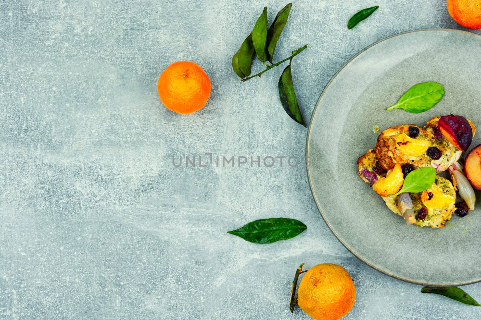 Pork chop cooked with plums and tangerine. Baked meat steak meat in sweet fruits sauce