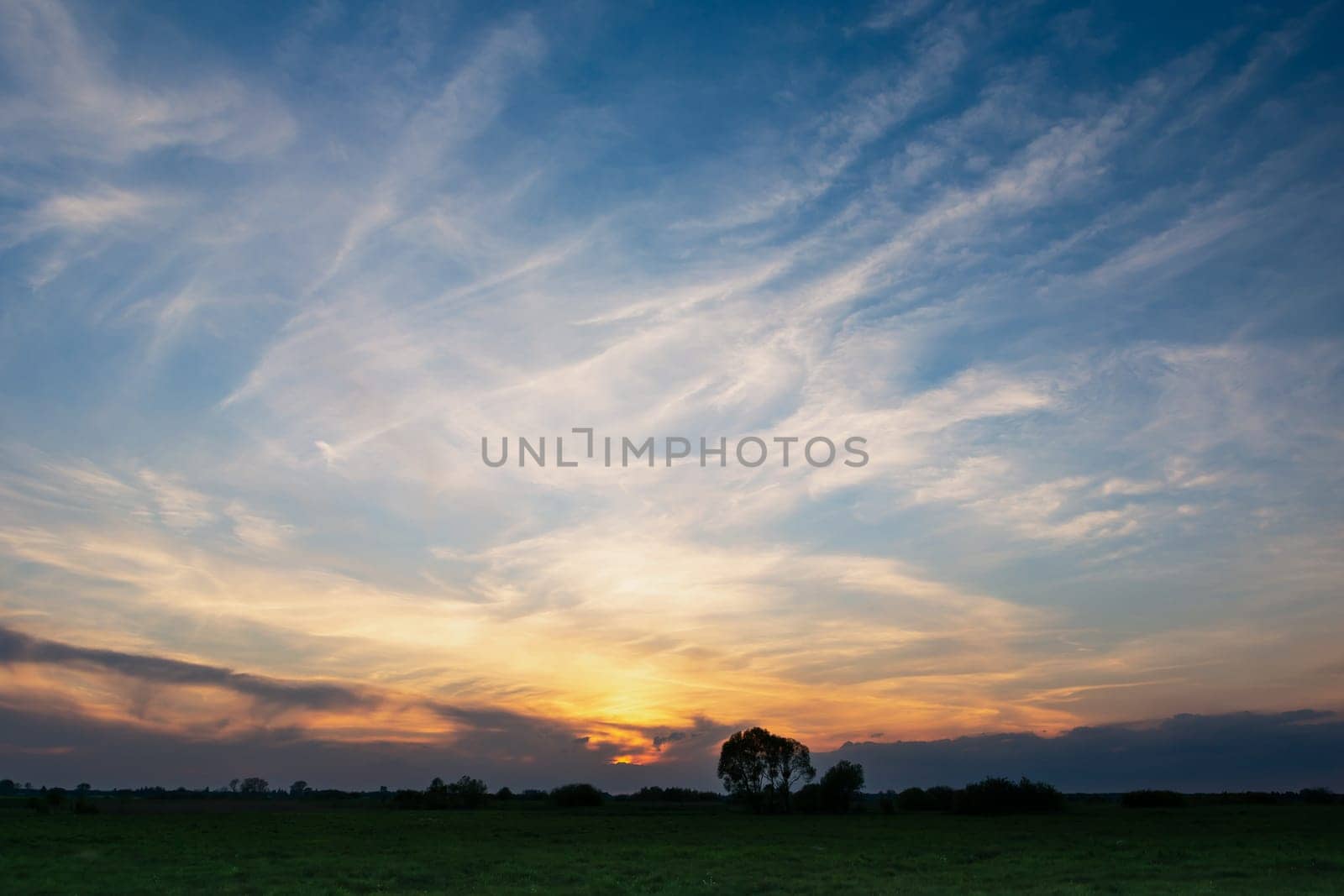 White clouds on blue sky after sunset, photo with low horizon