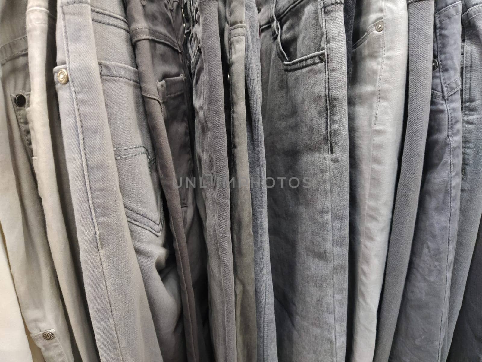 Clothes hung on hangers. Assortment of second hand store. Clothing hanging on a rack, ready for sale to customers. Saving money in crisis. Cheap shopping. Jeans and pants