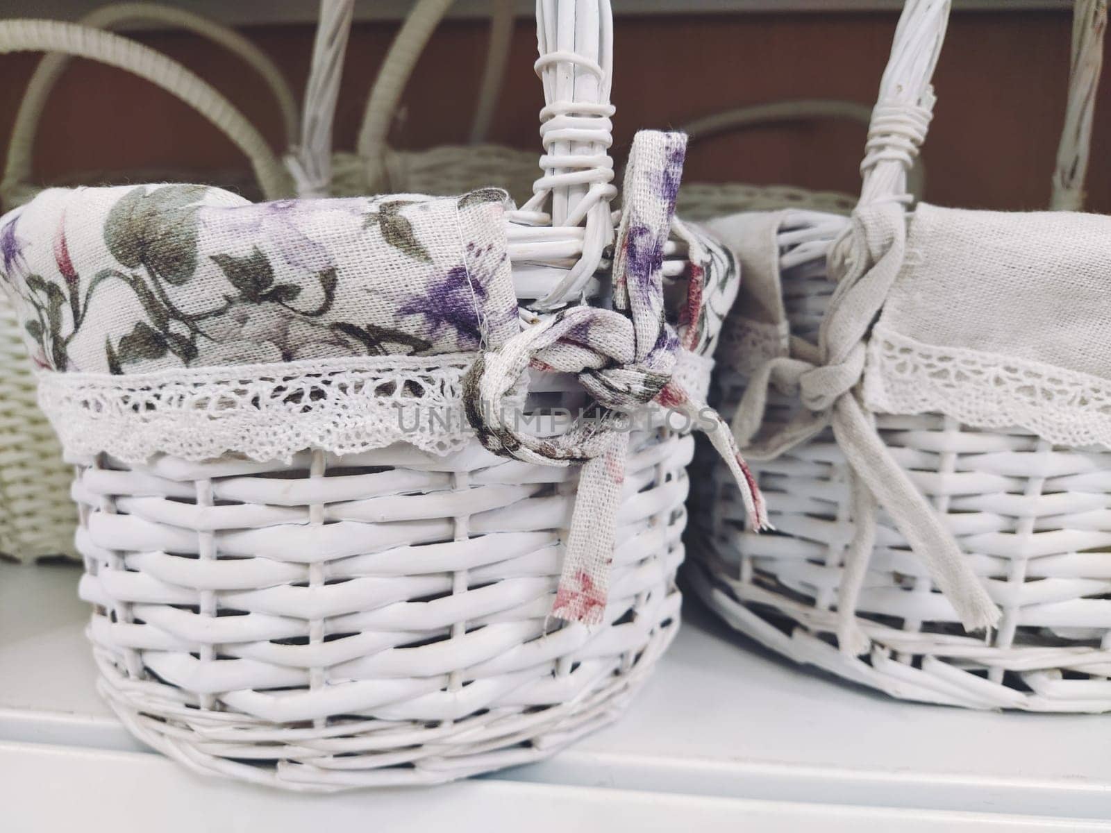 Wicker decorative baskets on a shelf in a store. Pretty baskets painted white. Textile bag. Stylish gift for Easter. Decor element of the interior of an apartment, a country house or a spring garden