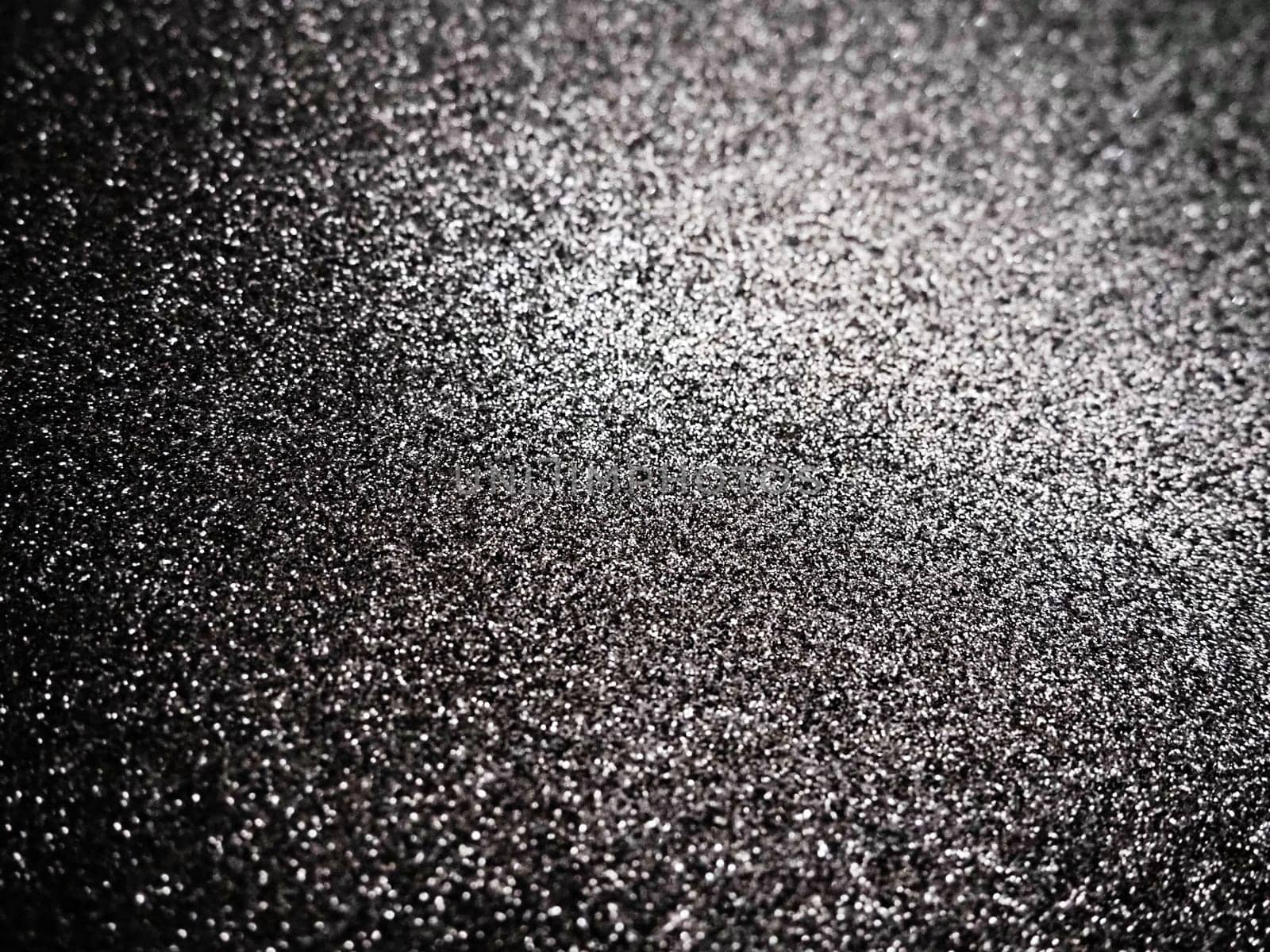Black glitter texture christmas background. Bent shiny velvet paper.