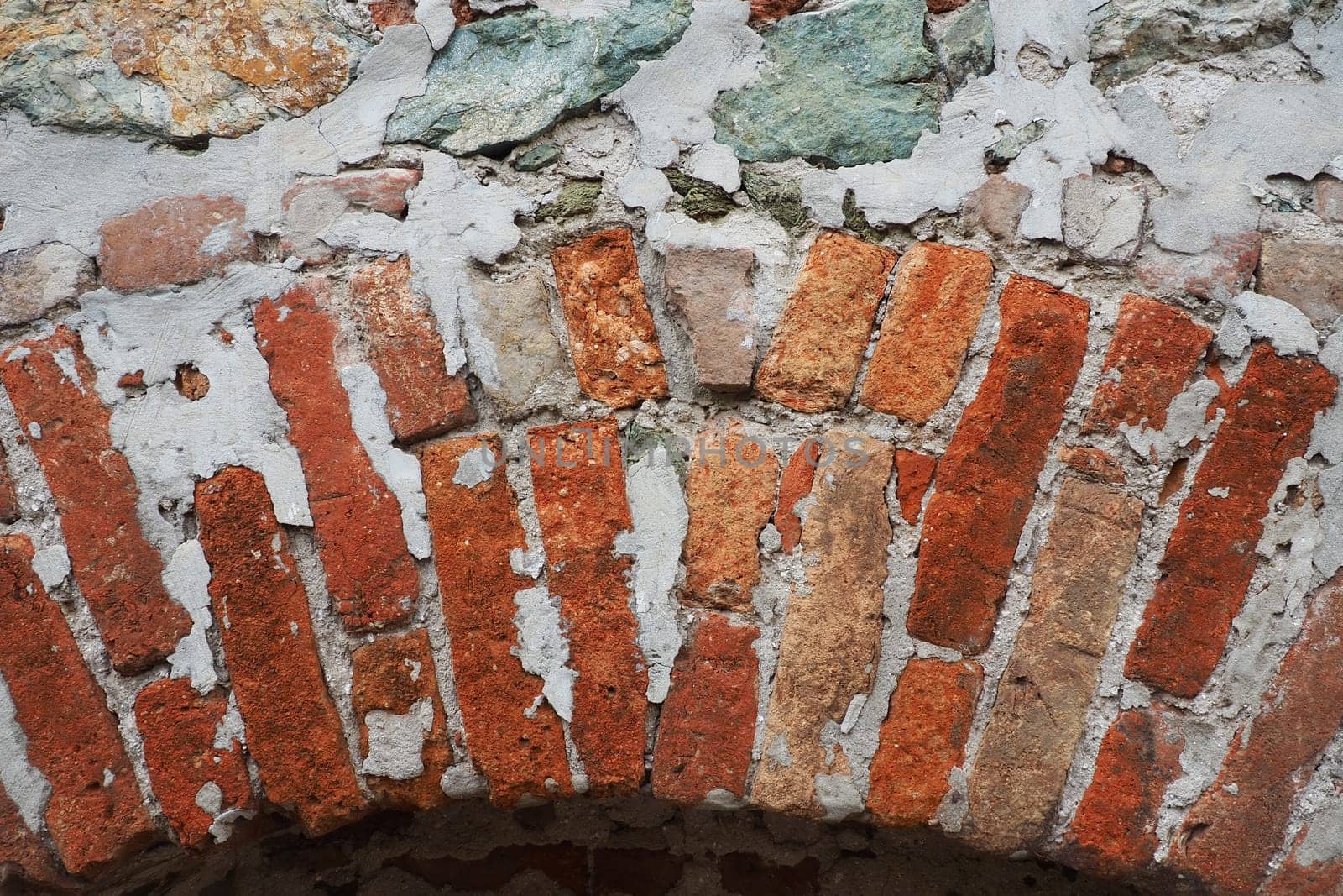 Brick wall of an ancient fortress. Uneven red and brown bricks with cement. Brick background