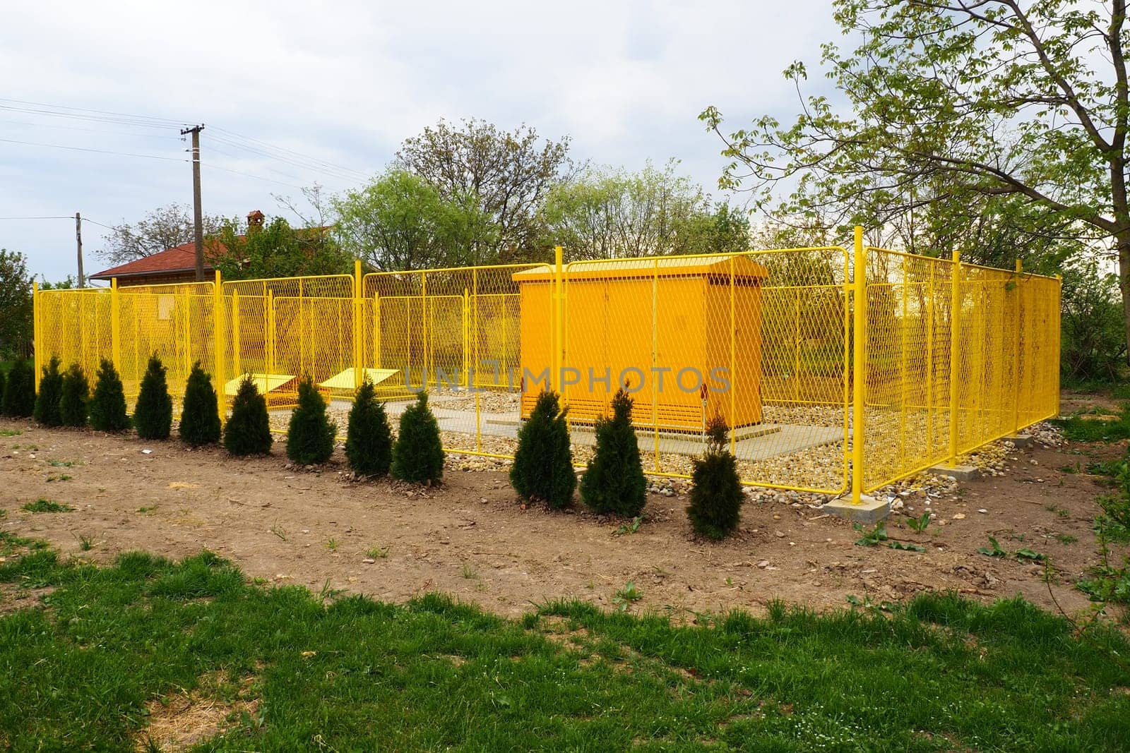 ground with tanks for liquefied gas. Modern gas installation with protective fencing. Yellow fence. Supply of gas to population. Connection of houses to energy. Gas and energy prices. Planted thuja.