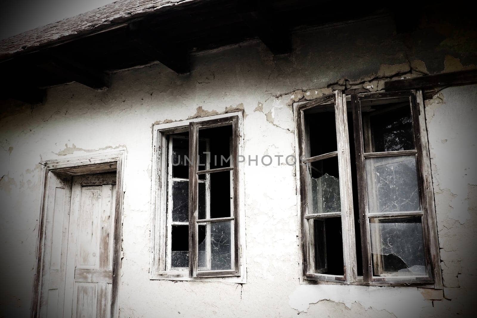 Abandoned spooky old house. Wooden windows and doors. The hut is a mud hut. Samani house. White stucco plaster. Halloween theme. Aging, loneliness, departure, war and devastation. Ukraine, Donbass.