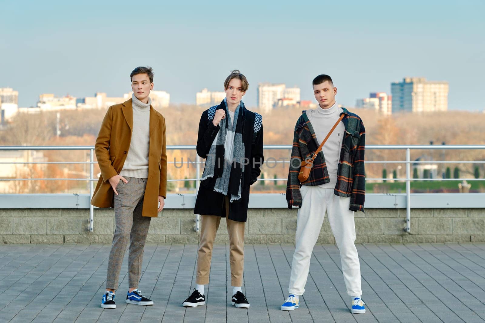 Three young men in autumn clothes standing on the street