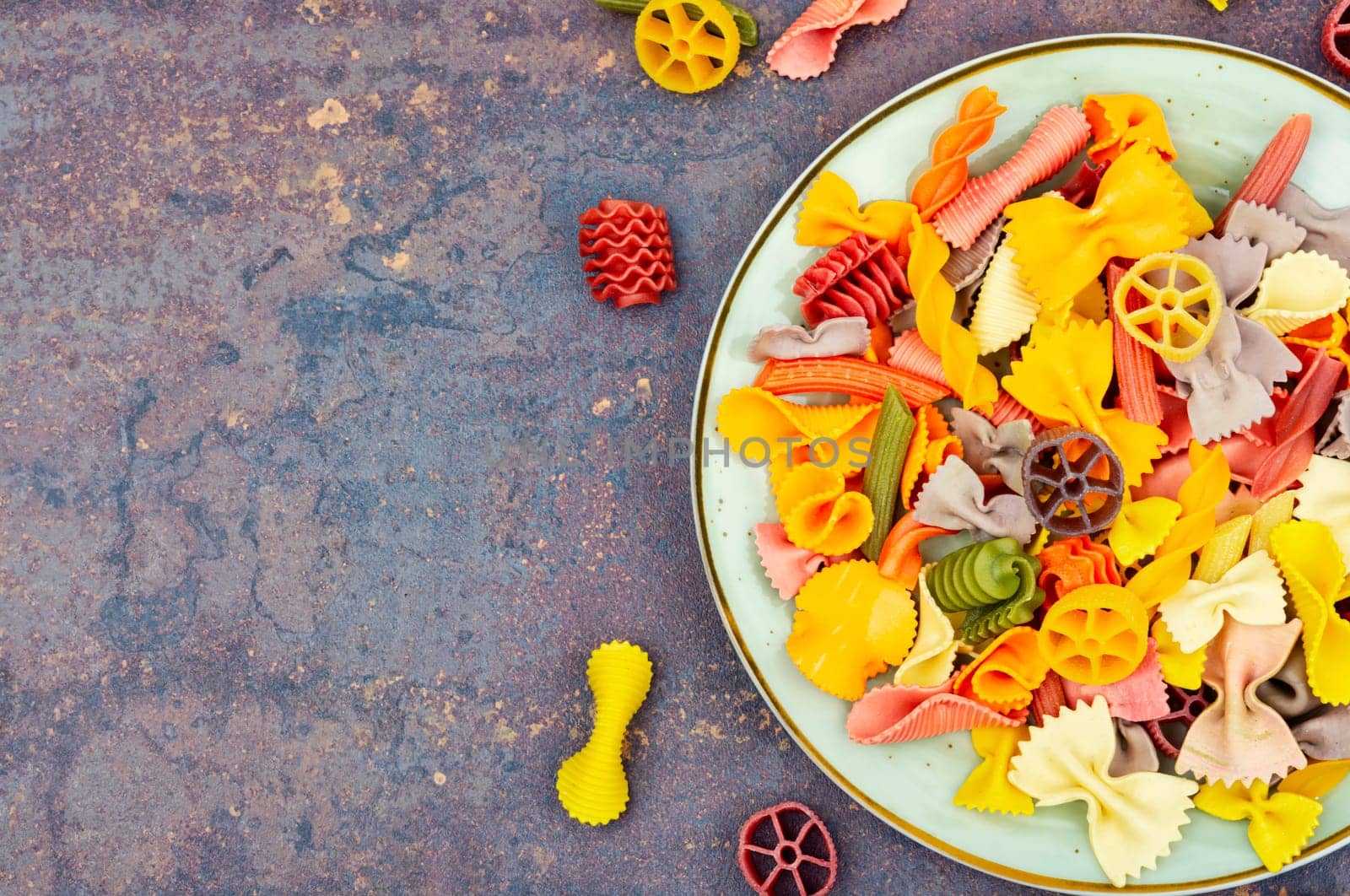 Colorful italian raw pasta on plate. Different types of Italian pasta. Space for text