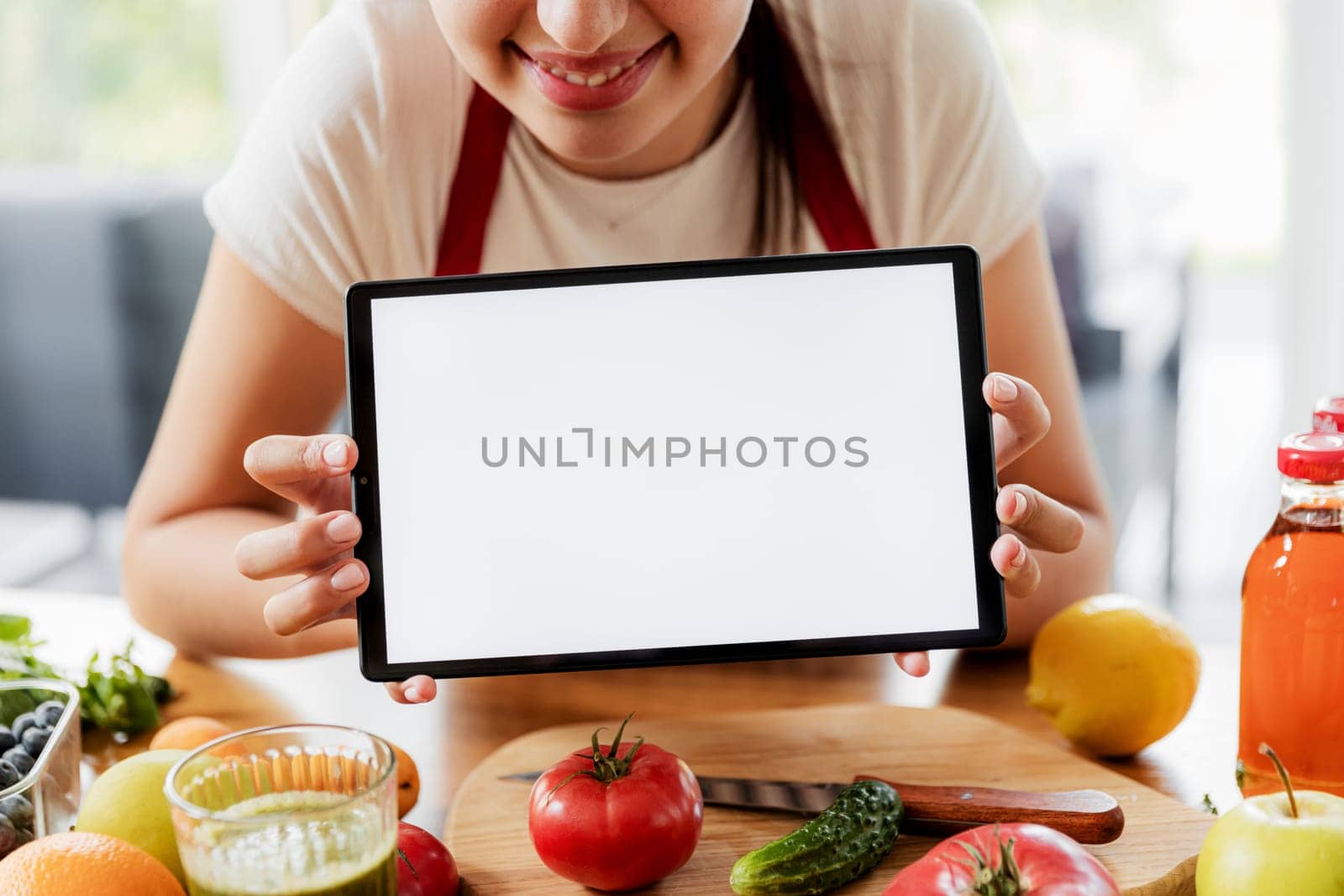 Woman hands holding tablet, showing white empty blank screen mockup at kitchen while healthy vegetable breakfast cooking. Online grocery food shopping. Delivery app ads, cook book, diet plan recipes