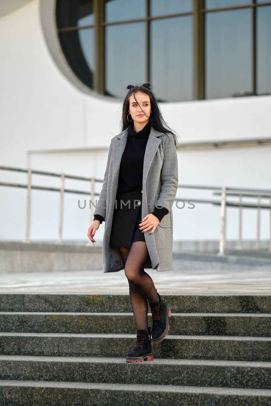 Young woman in spring-autumn casual outfit descending the stairs outdoor
