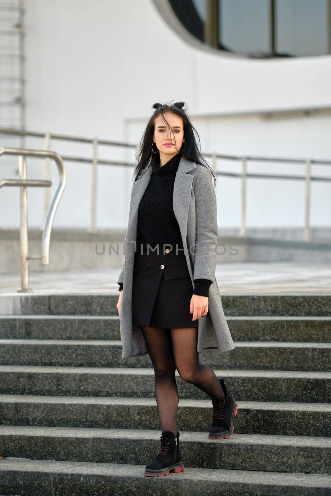 Young woman in spring-autumn casual outfit descending the stairs outdoor