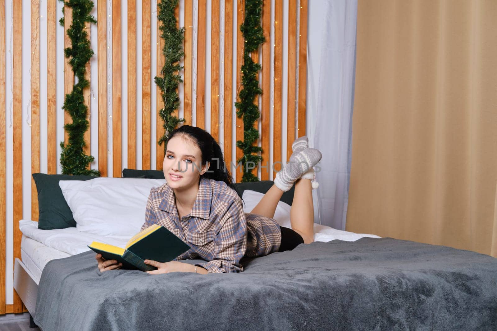 Clever young woman reading the book in bed during vacation