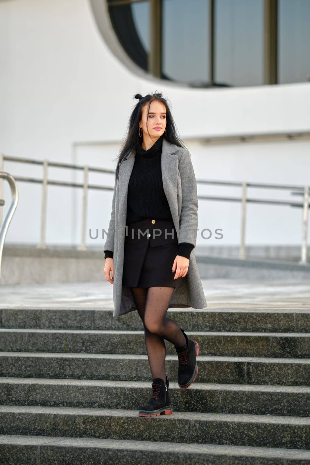 Young woman in spring-autumn casual outfit descending the stairs outdoor