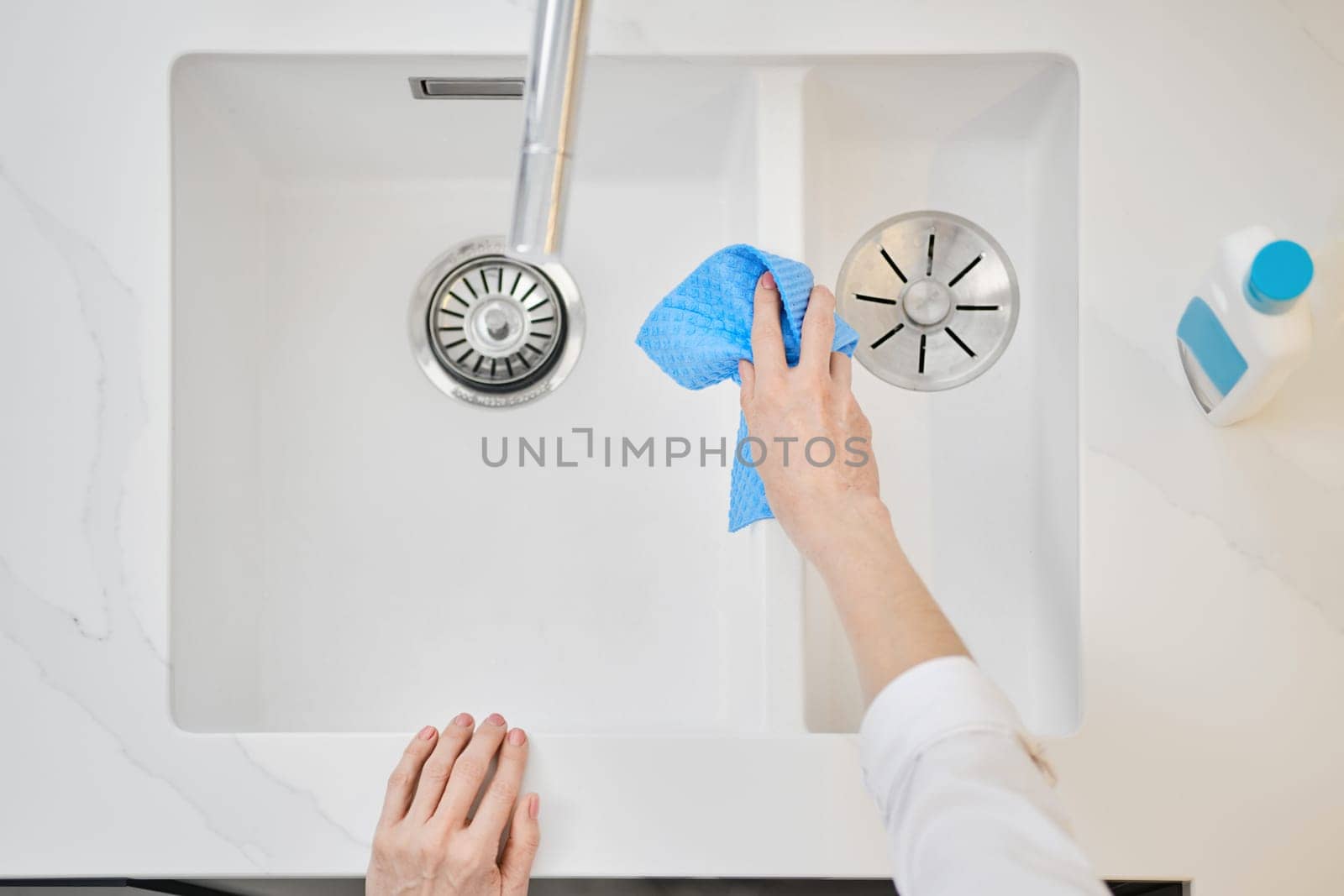 Overhead view of female hand with sponge washing the sink (focus on one hand)