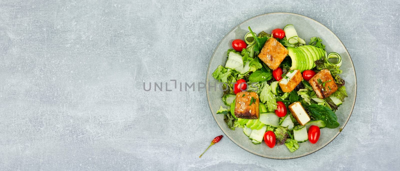 Homemade lettuce salad with cucumber, avocado and fried tofu soy cheese. Healthy lifestyle