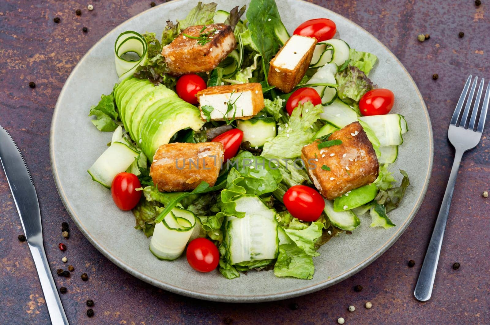 Homemade lettuce salad with cucumber, avocado and fried tofu soy cheese. Healthy lifestyle
