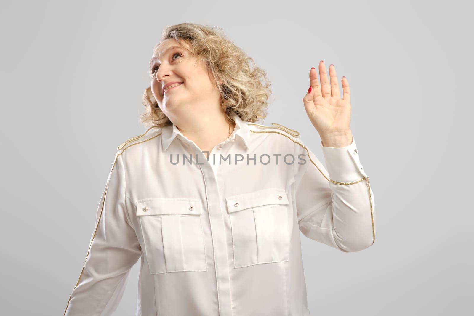 Senior woman waves her hand in disbelief over grey background
