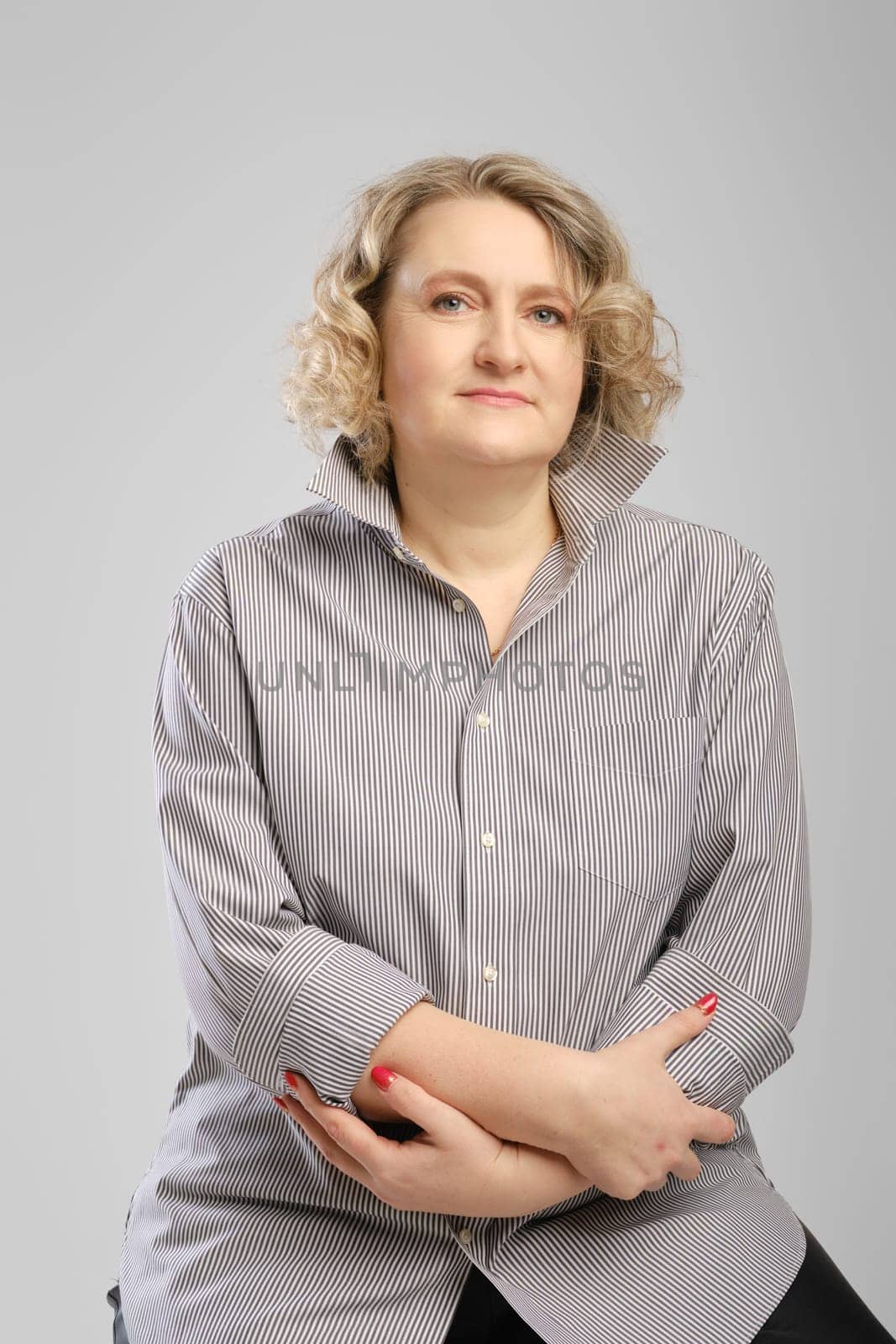 Studio portrait of senior woman in grey shirt with crossed arms