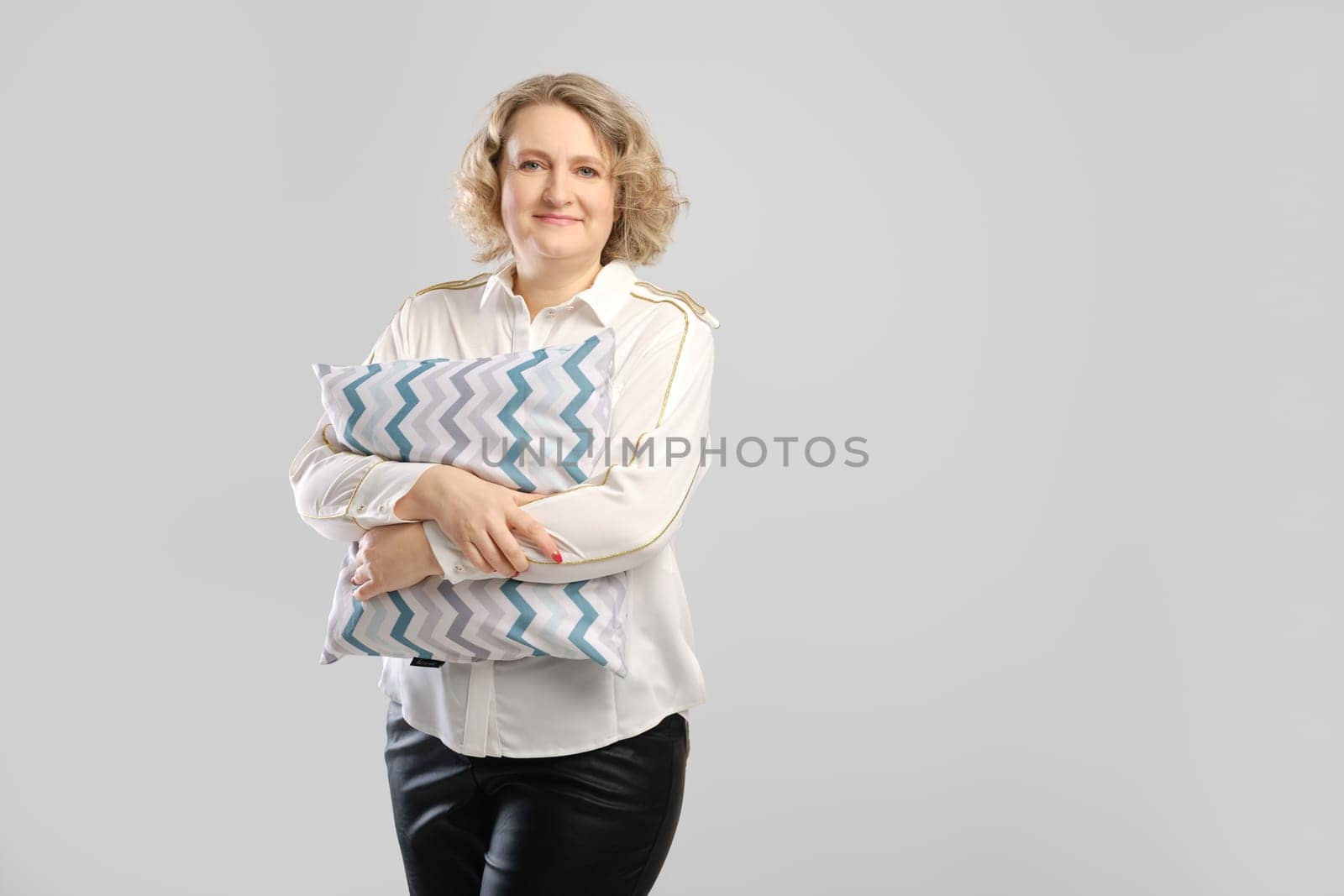 Senior woman holds small pillow in hands