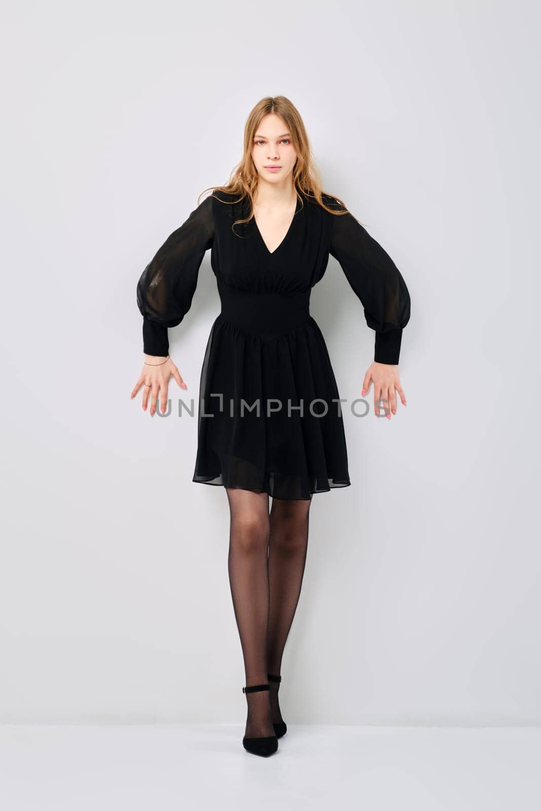 Tense young woman pushes off with her hands from grey wall, leaned forward