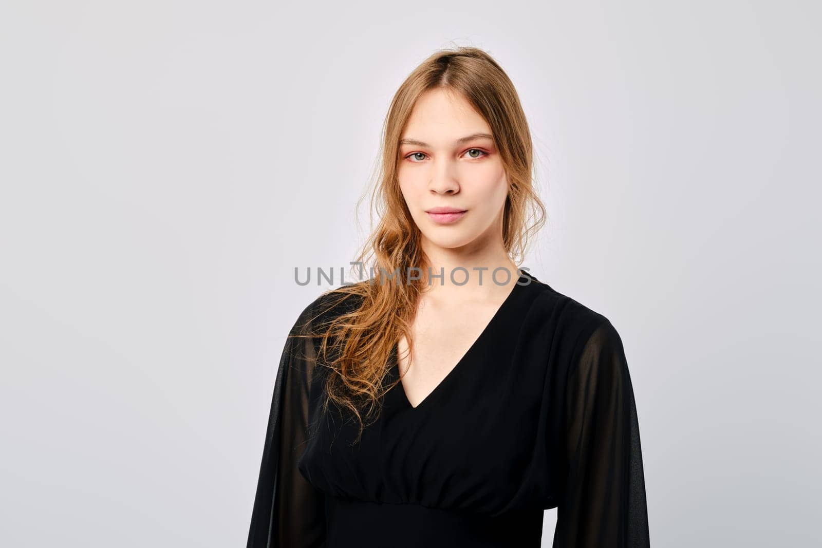 Studio portrait of calm and positive young woman looking straight over grey background