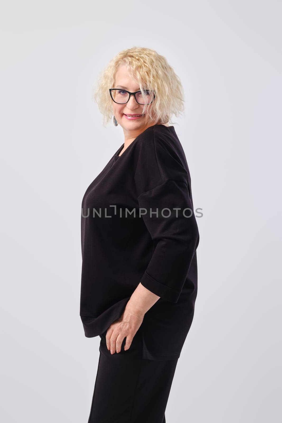 Portrait of smiling middle aged woman with short blond curly hair standing in profile