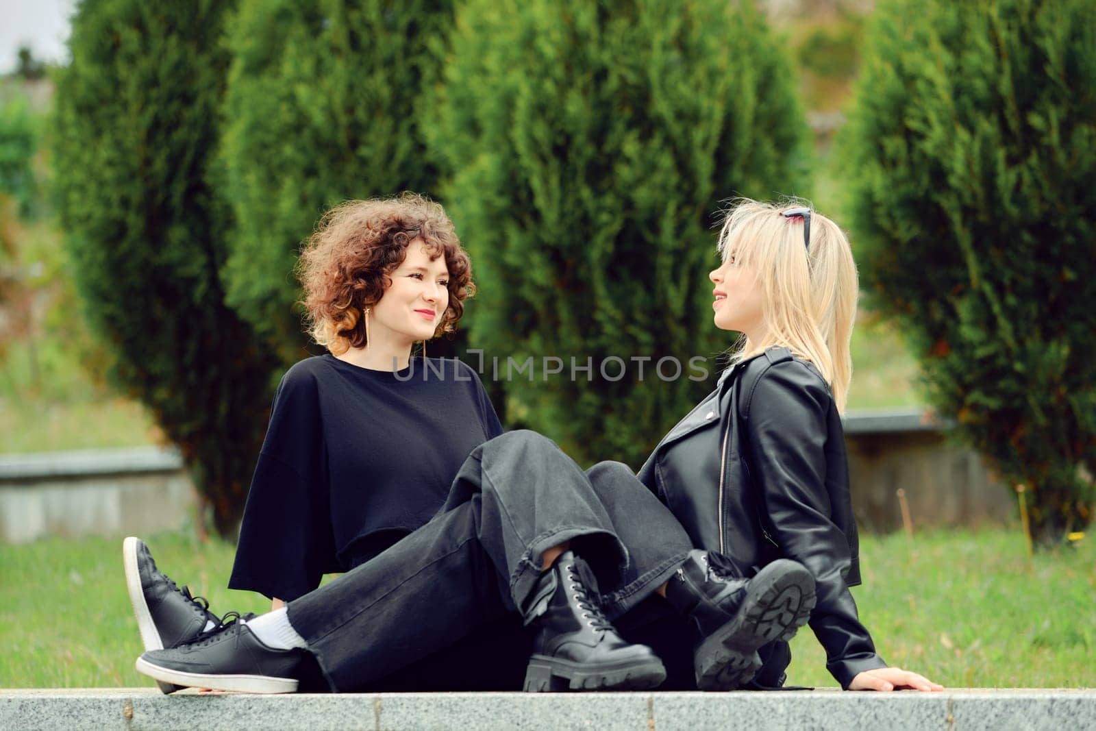 Two young best friends sitting next to each other in the park