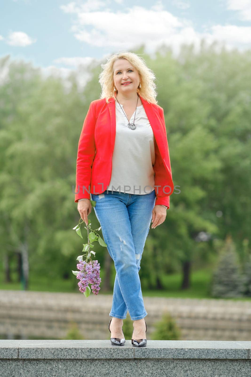 Beautiful middle-aged woman with lilac branch in hand