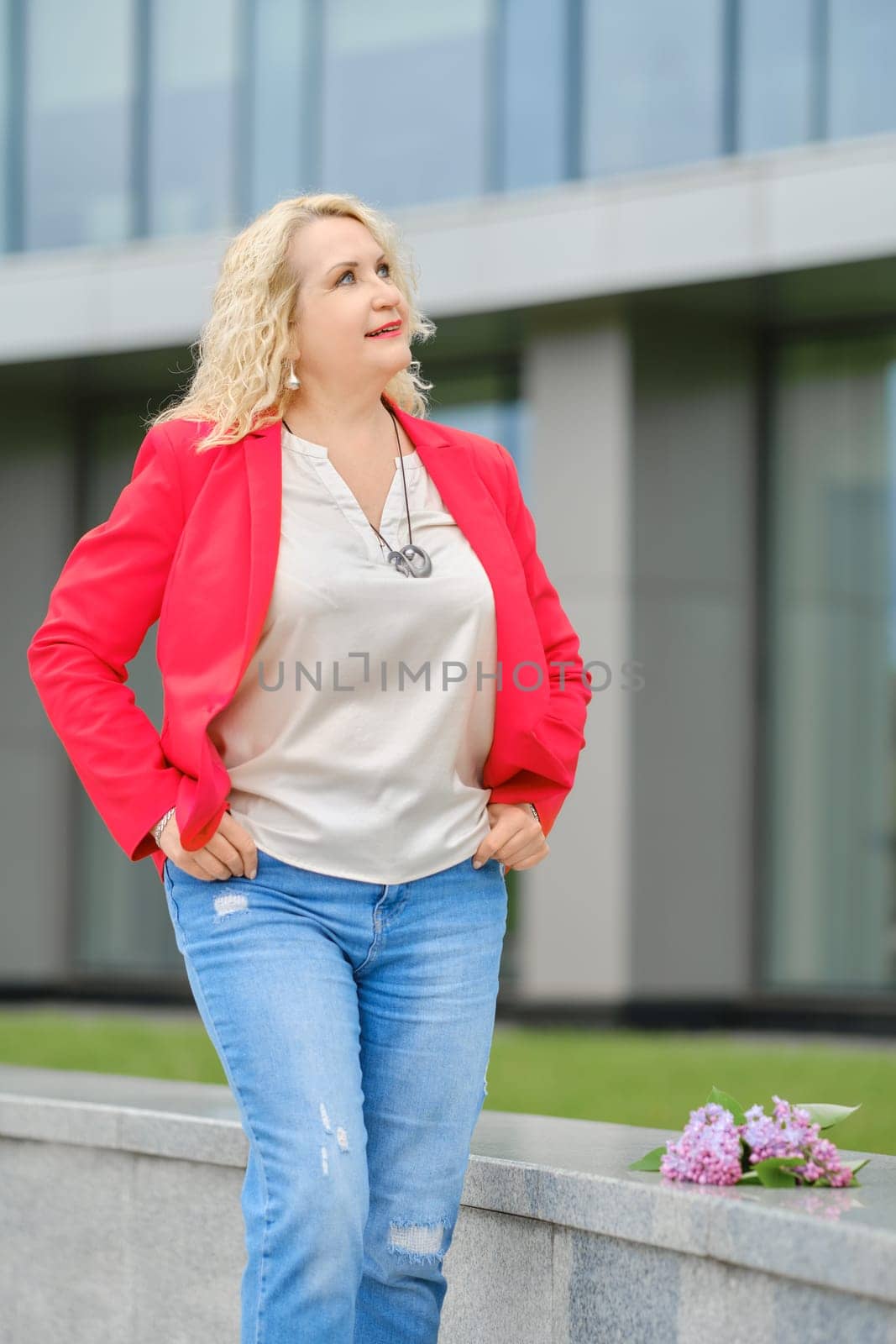 Senior woman standing near the modern building and looking up