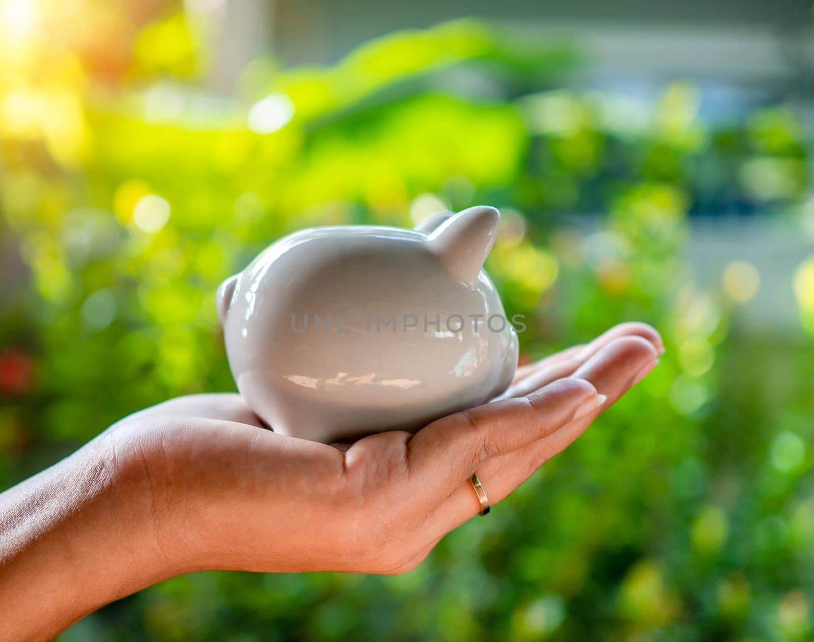 Hand human and Piggy bank on natural bokeh background. saving concept