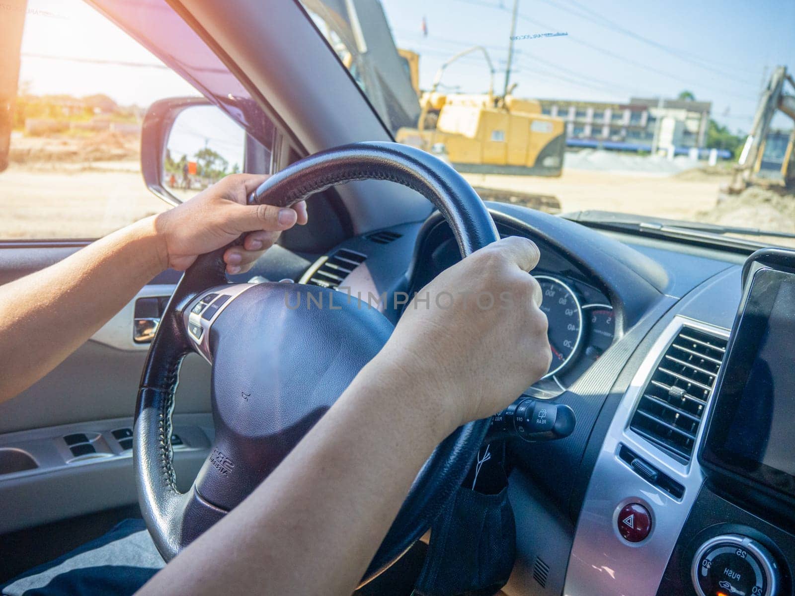 A man's hand held the steering wheel of a car to steer while the car was moving away. Concept and direction of business operations according to the plan. Direction control concept.