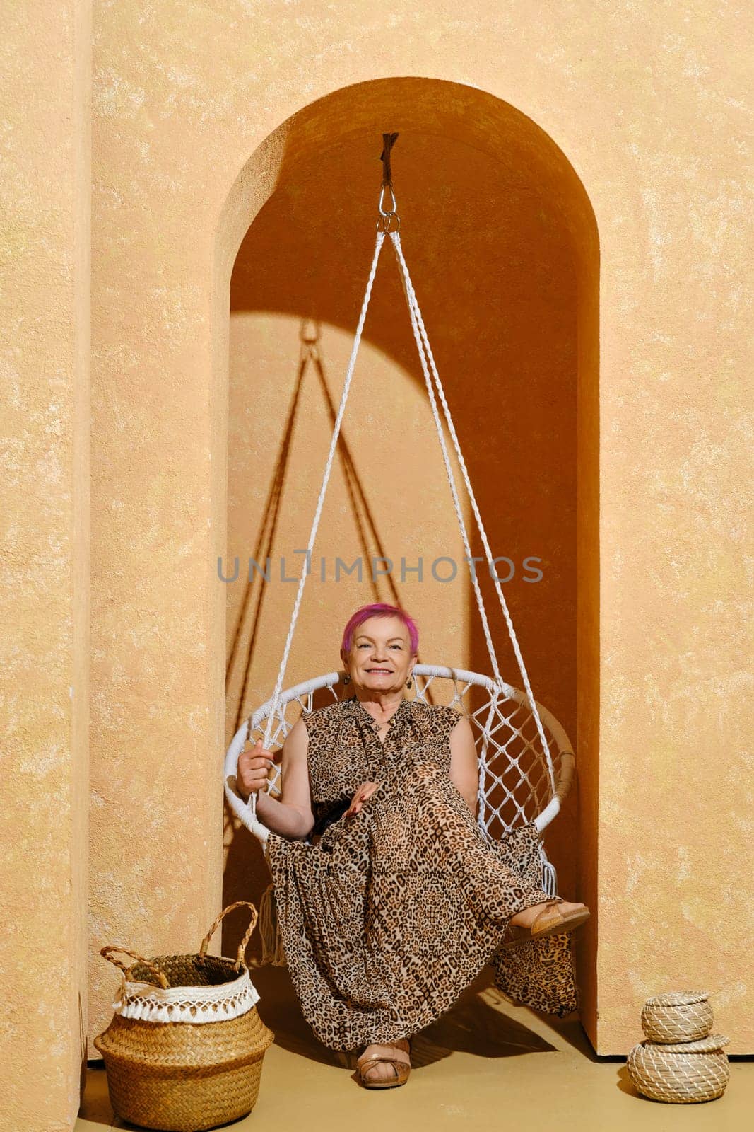 Retired woman sits in wicker swing in arch