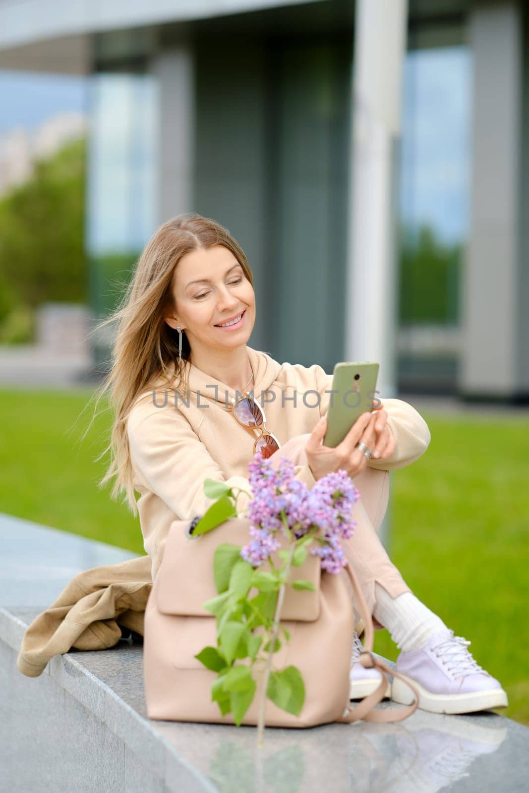 Middle aged woman dialing phone number outdoors