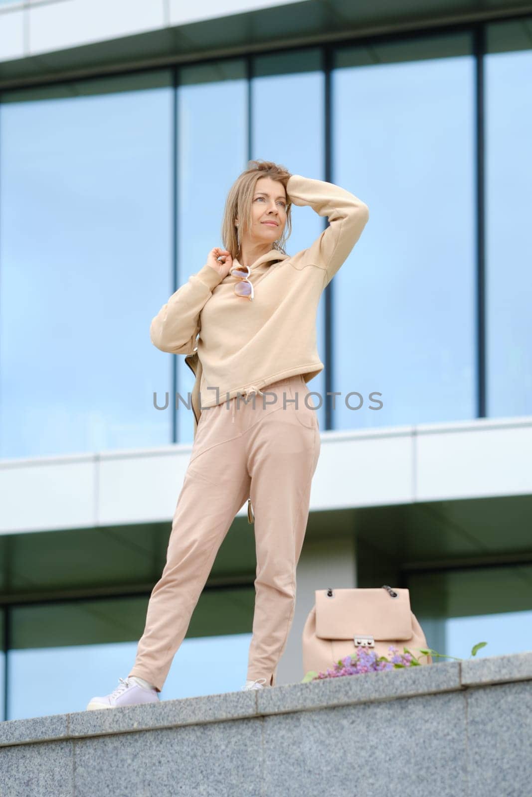 Sportive middle-aged woman looks into the distance and straightens her wind-blown hair