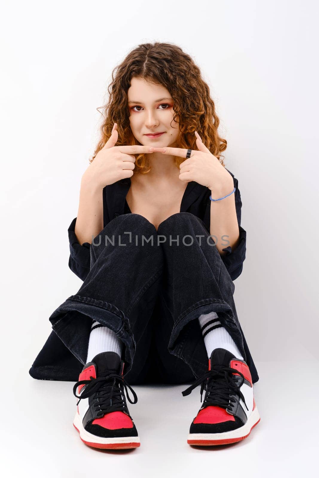 Lovely teenager girl sits on the floor and touching her fingertips