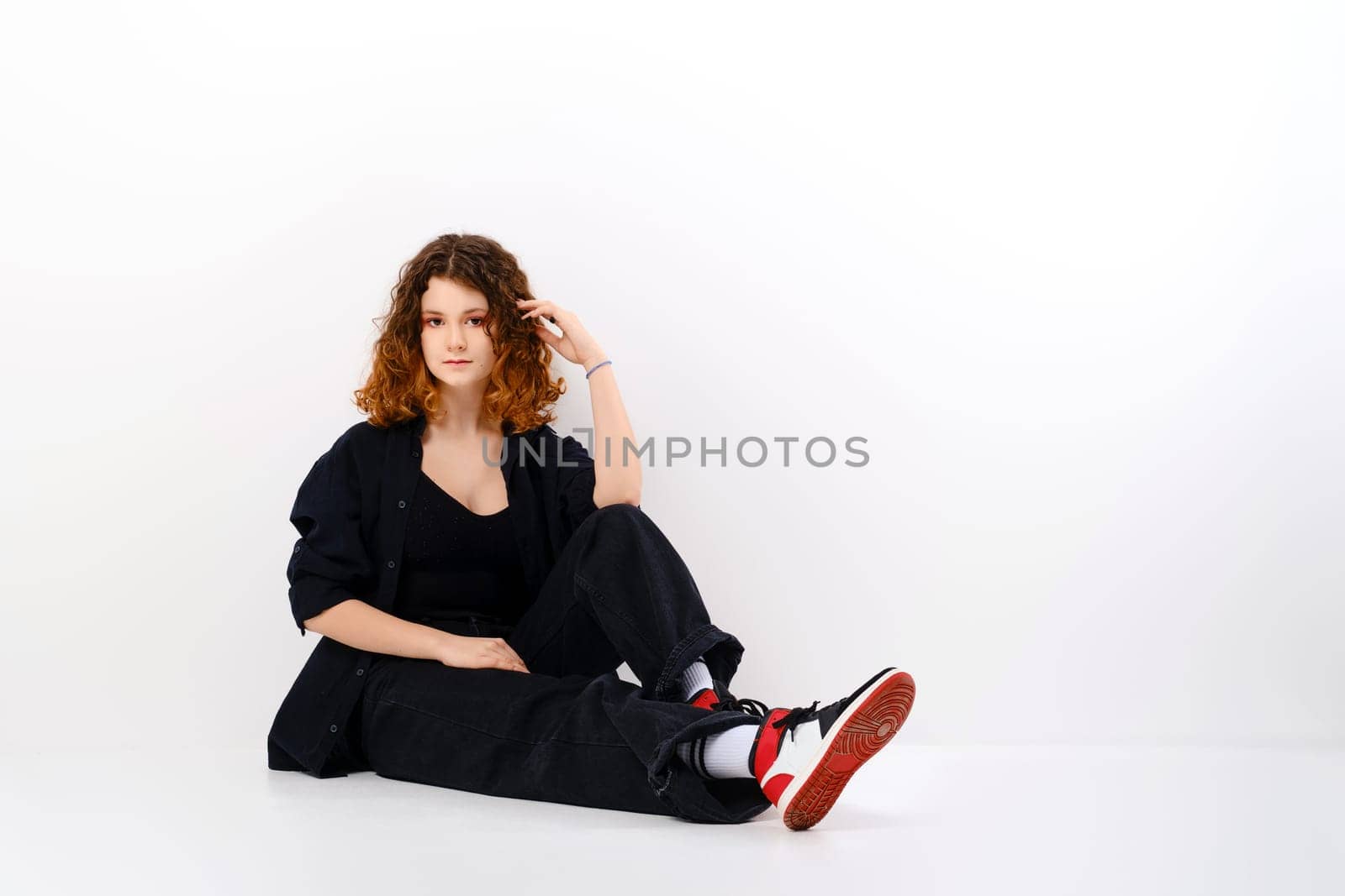 Teenager girl with colored hair sitting on the floor in white studio