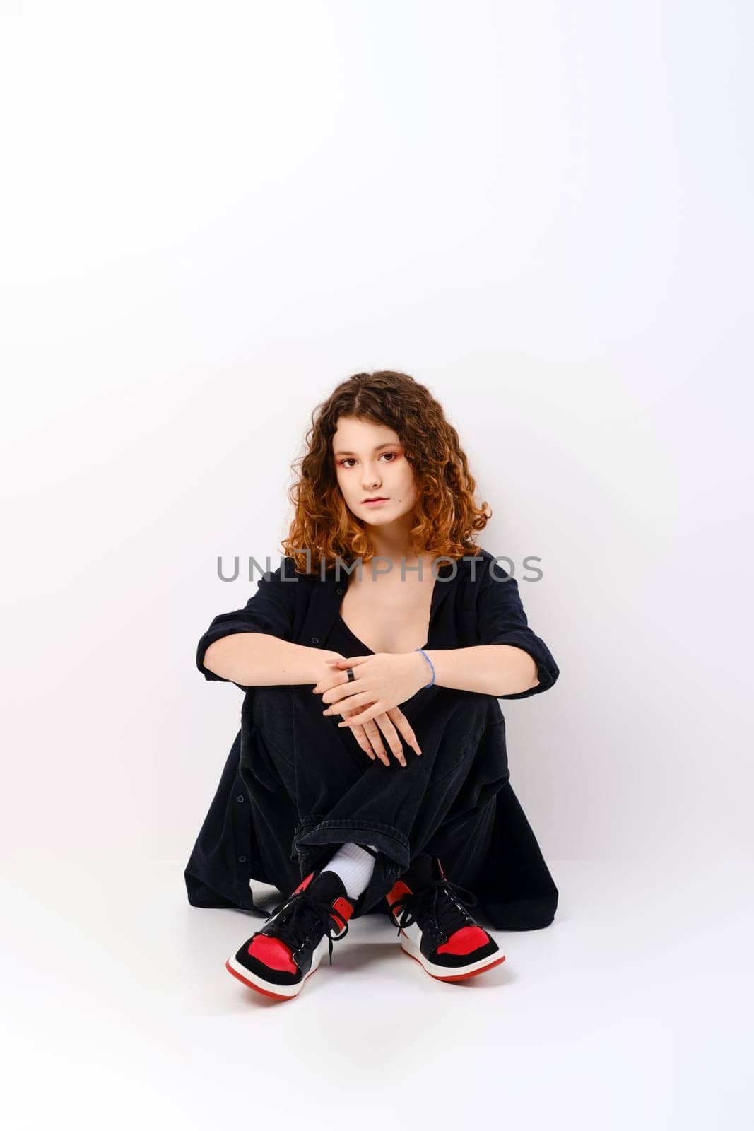 Cute girl sitting in studio on the floor with crossed legs