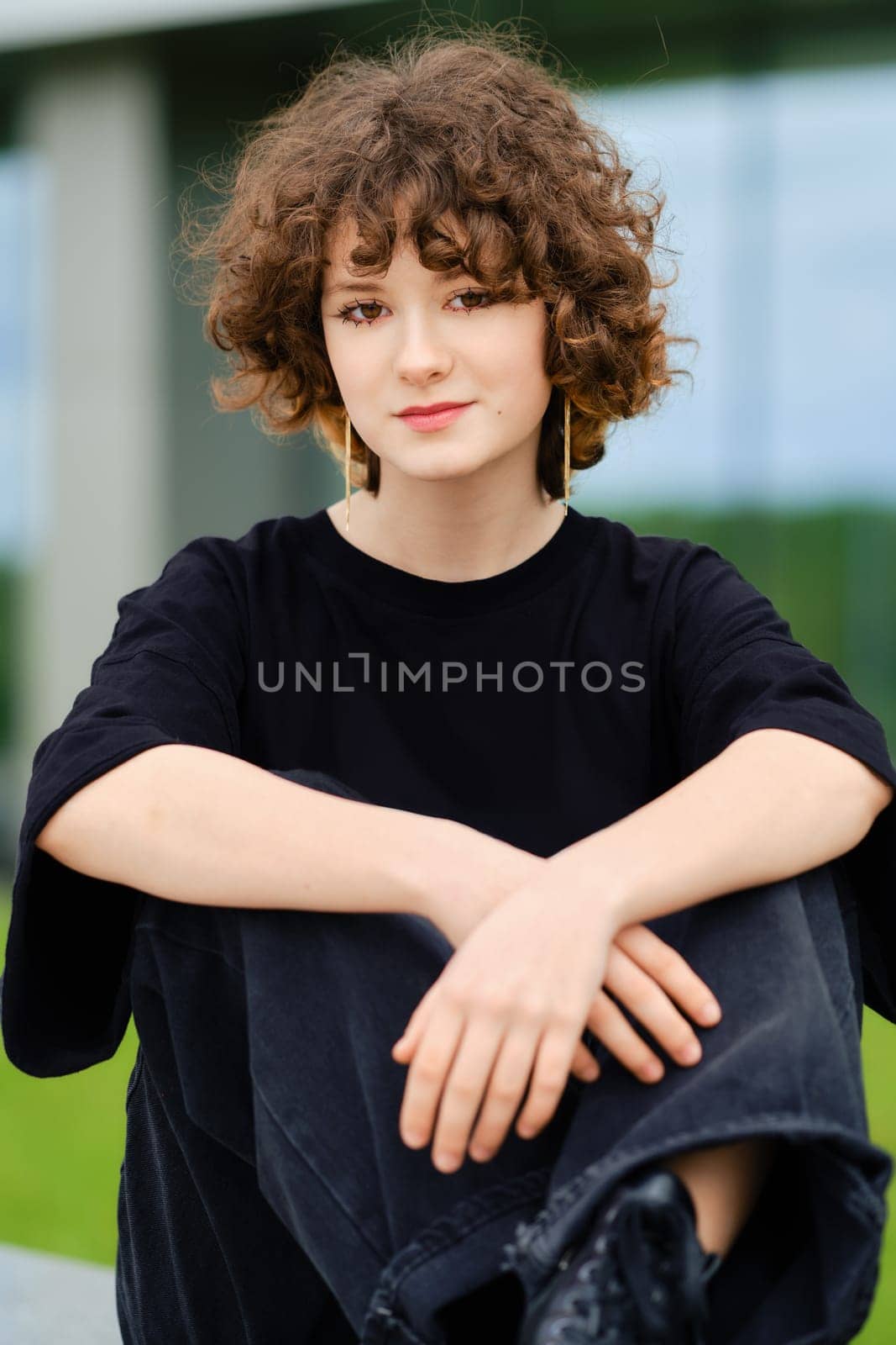 Portrait of cute teenager girl in wide black jeans, shirt and rough boots outdoors