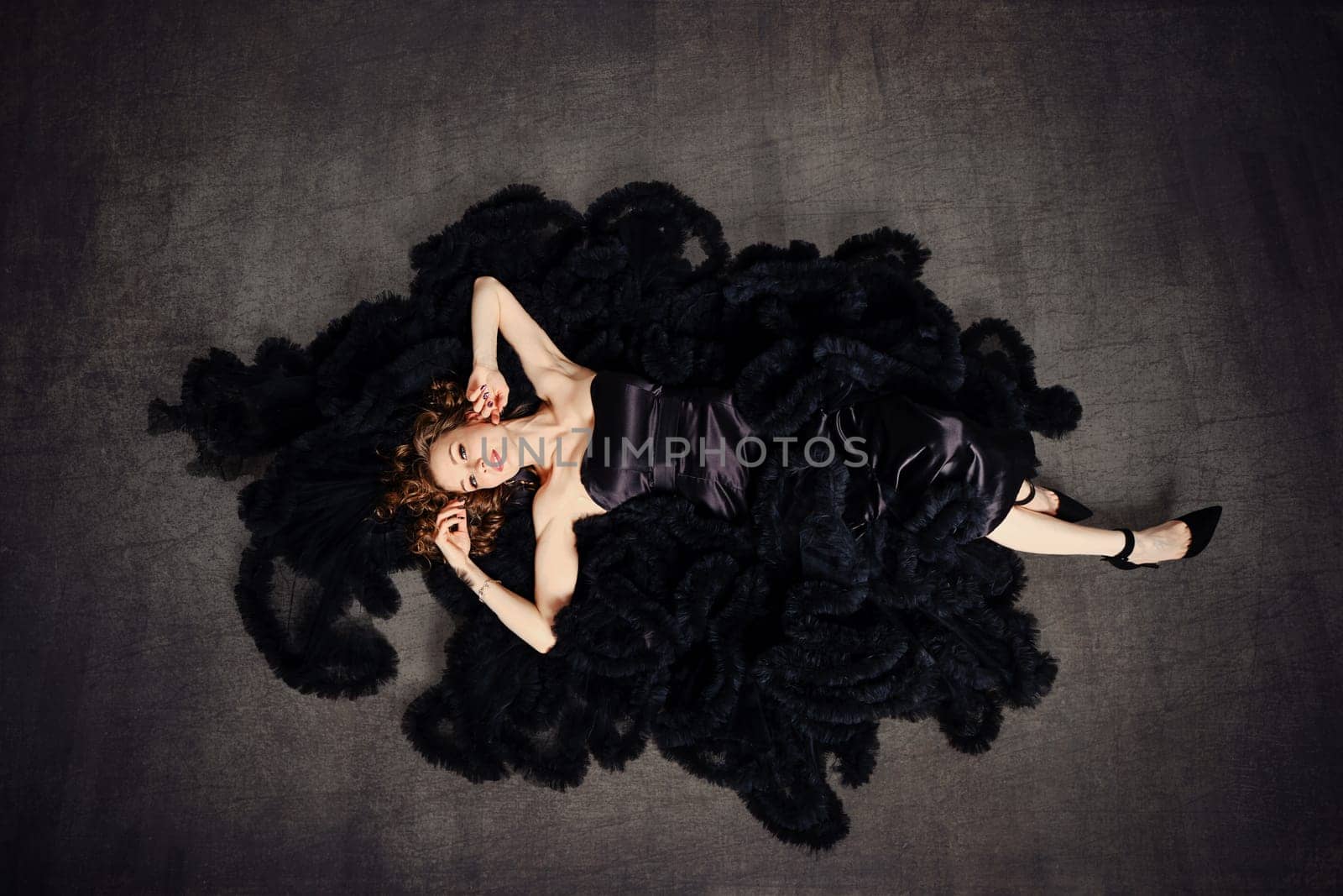 Fashion model in a luxurious puffy black dress lying on a floor