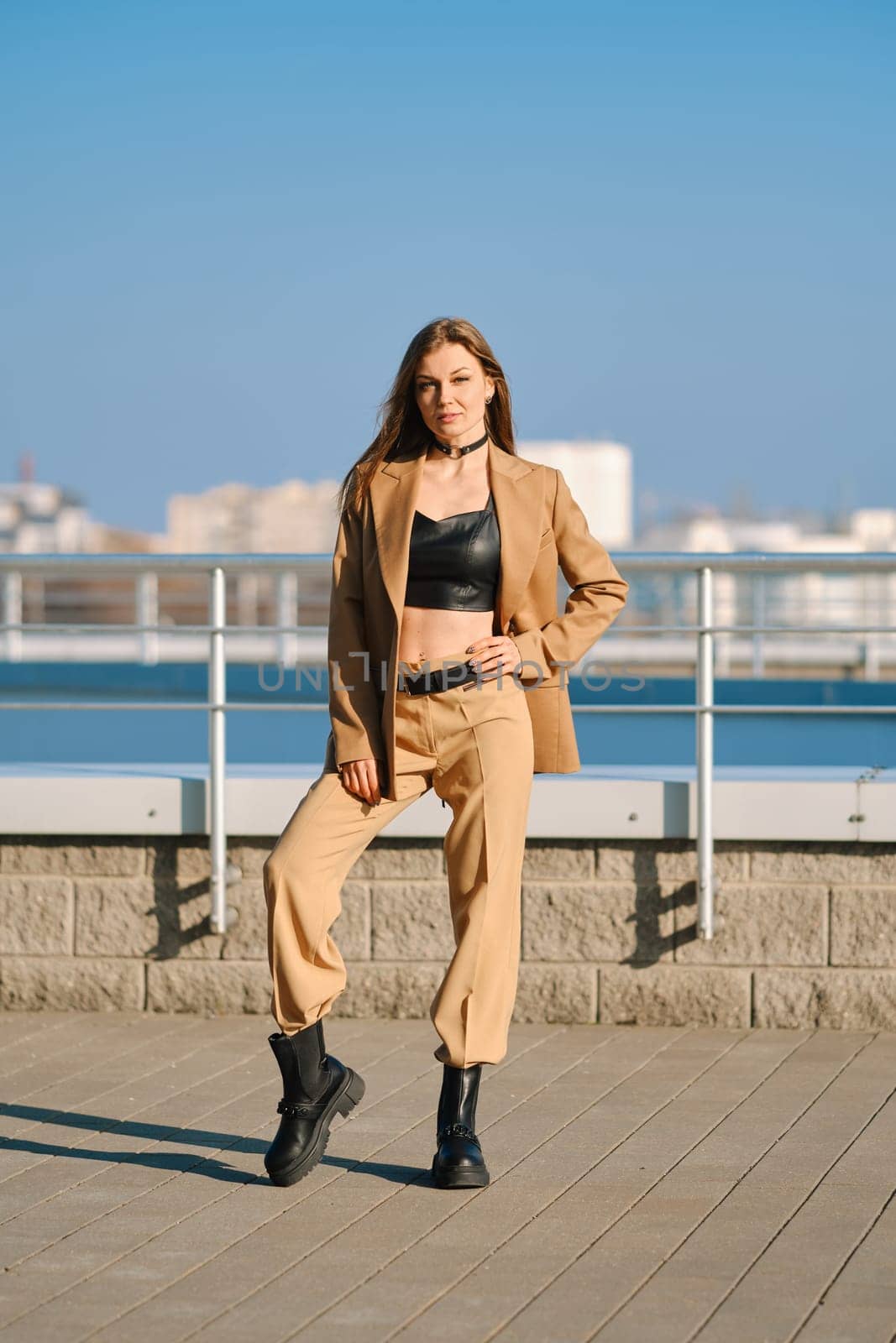 Street fashion, women casual and trendy outfit. Woman in pantsuit, leather tank-top and rough boots outdoor.
