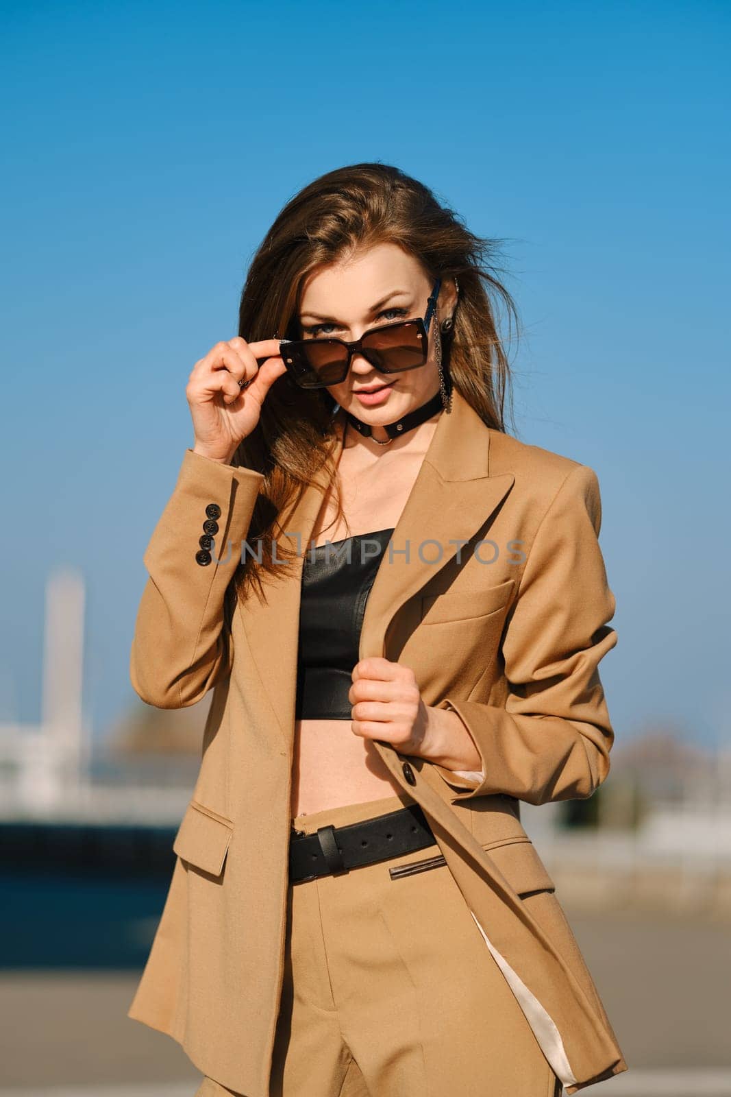 Street fashion, women casual and trendy outfit. Woman in pantsuit, leather tank-top and rough boots outdoor.
