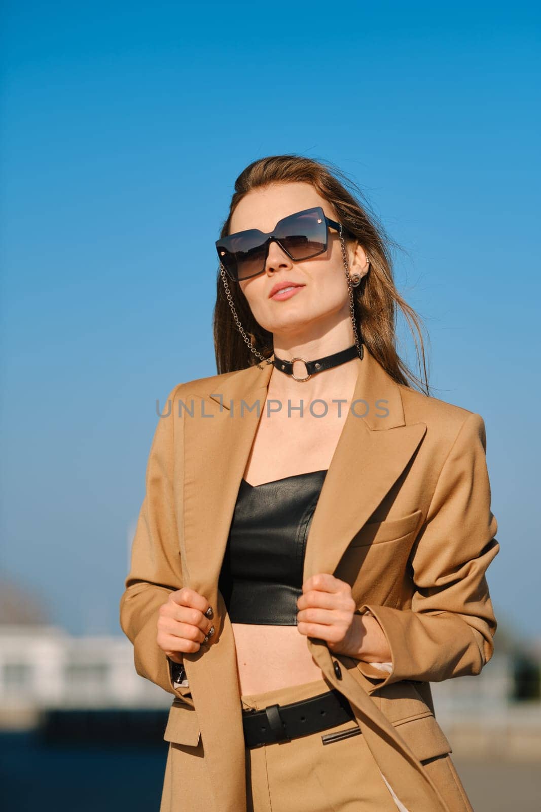 Street fashion, women casual and trendy outfit. Woman in pantsuit, leather tank-top and rough boots outdoor.