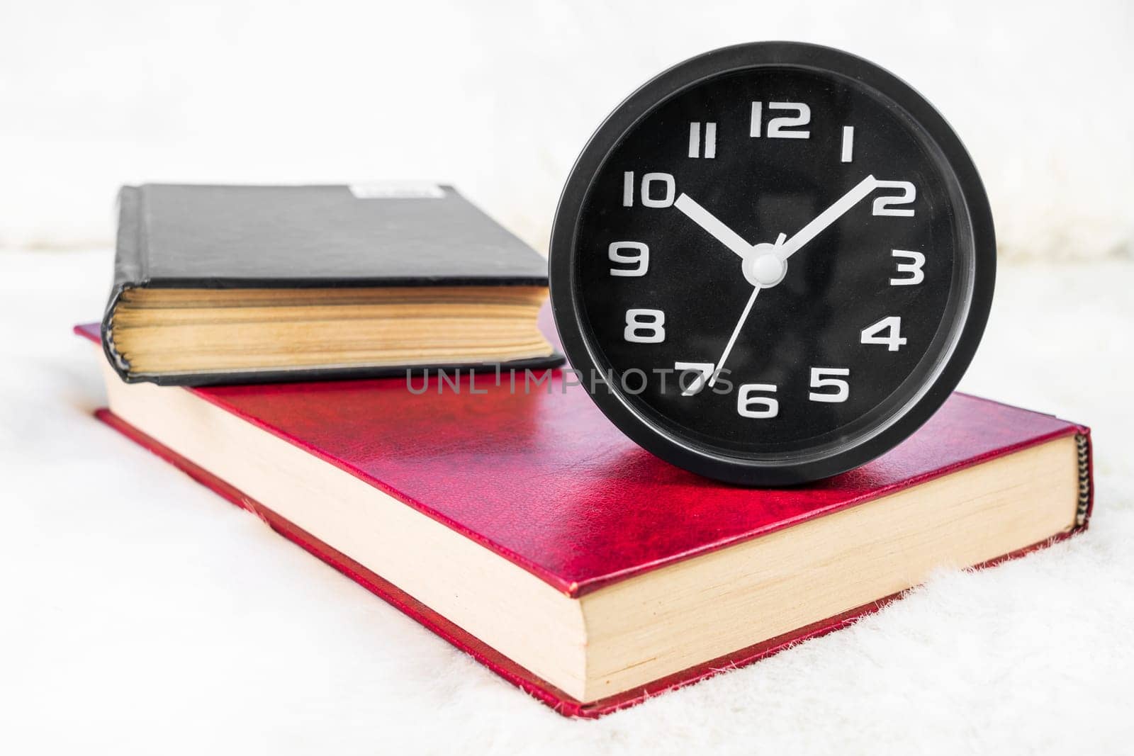 Close up Black alarm clock and book stacked on table