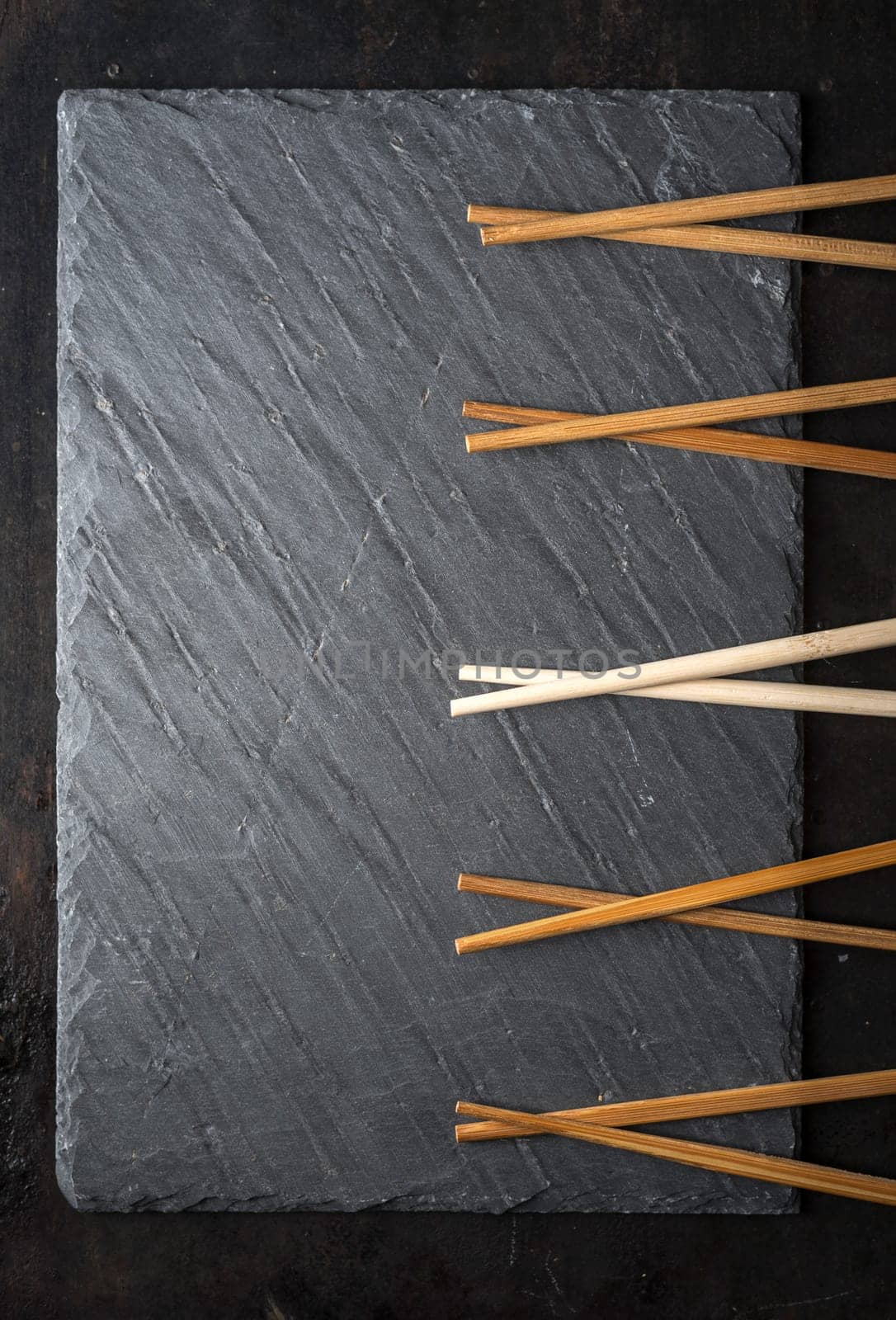Black sushi slate board with wooden chopsticks with copyspace. Top view. Asian food background.
