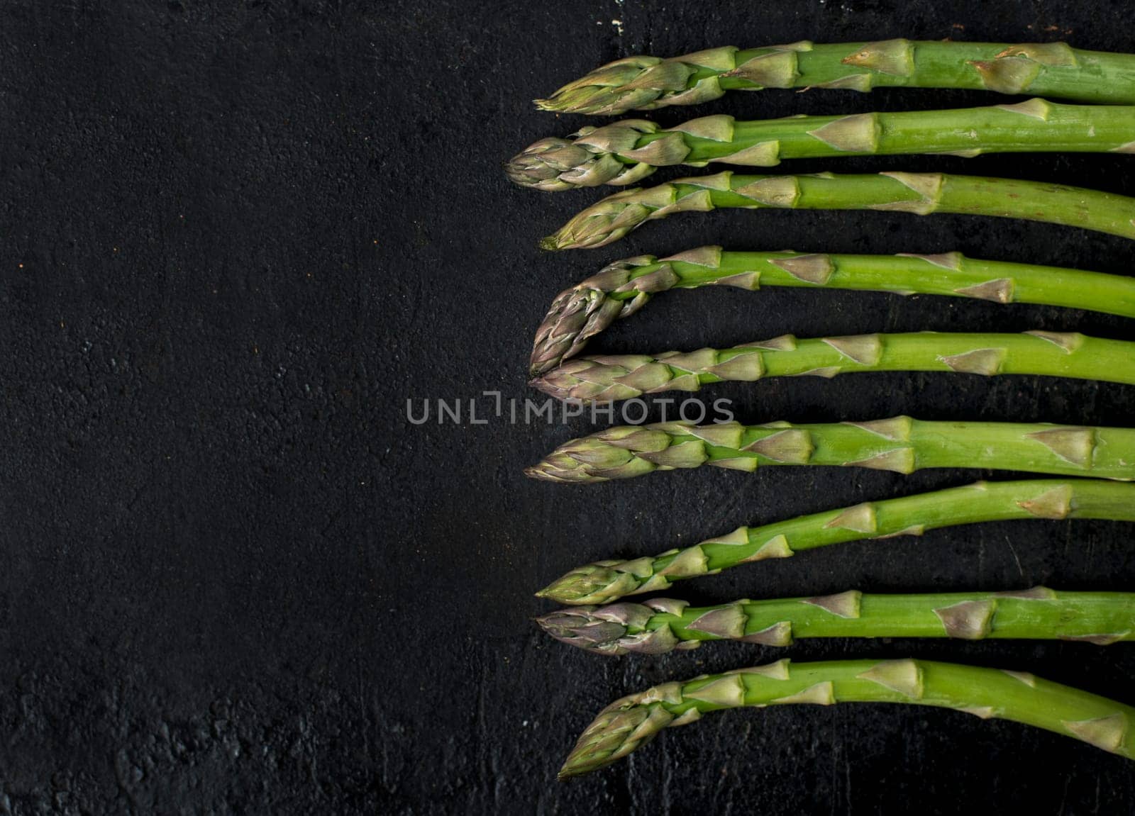 Top view of fresh green asparagus on rustic black board with copyspace. Food and cooking recipe background.