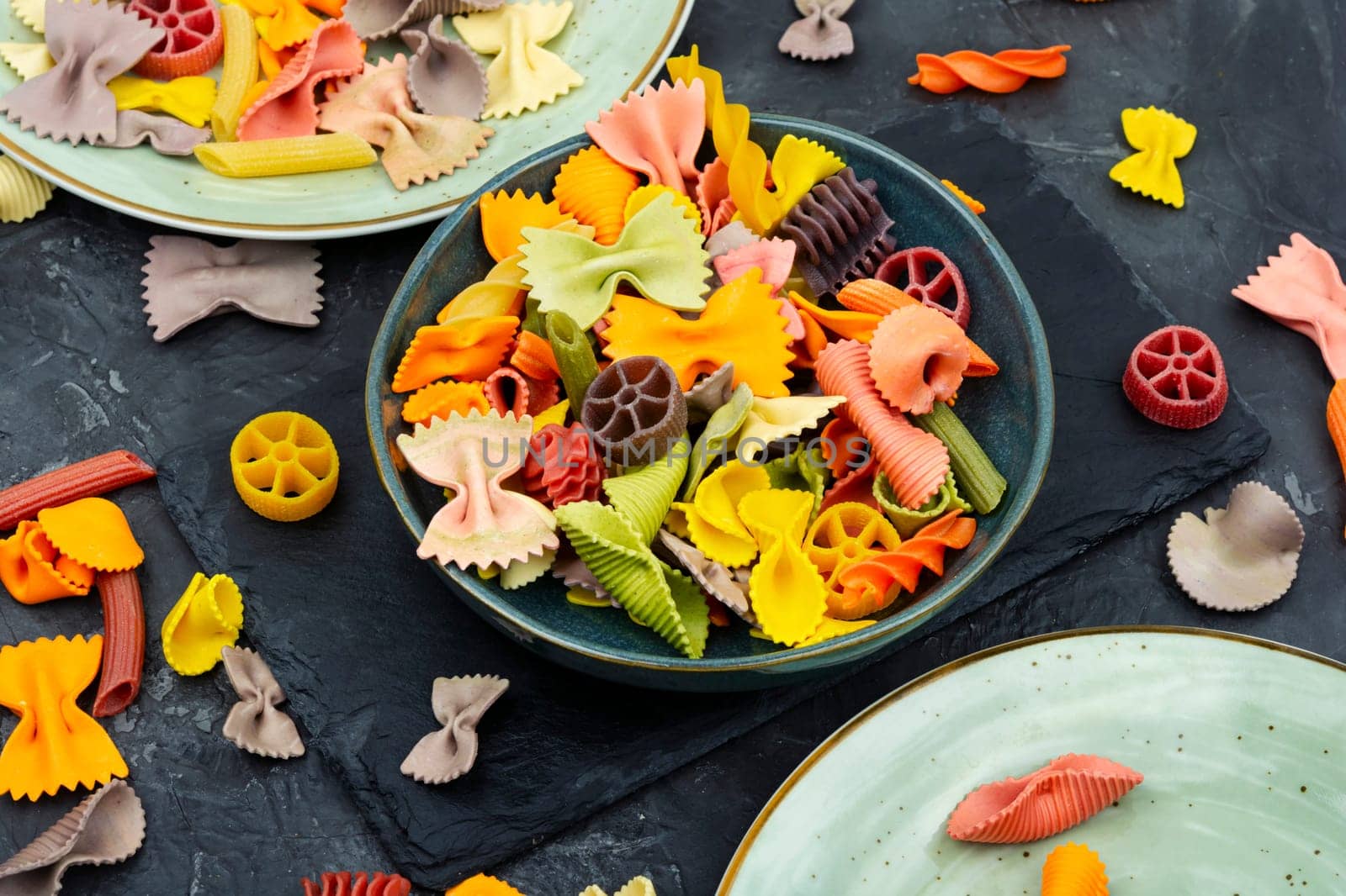 Colorful italian raw pasta on plate. Heap of colorful macaroni