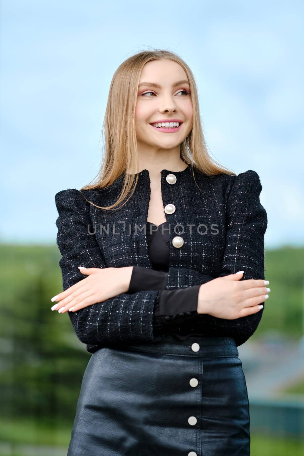 Outdoor portrait of smiling young woman with crossed hands