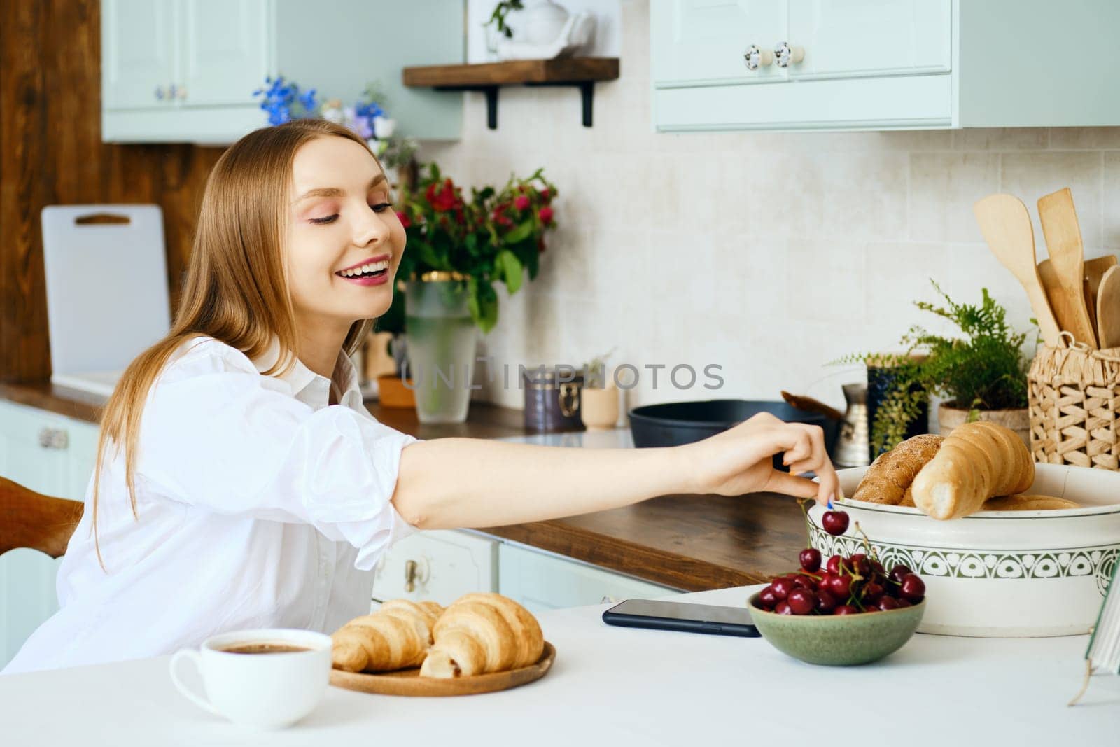 Young woman takes sweet cherry from a plate