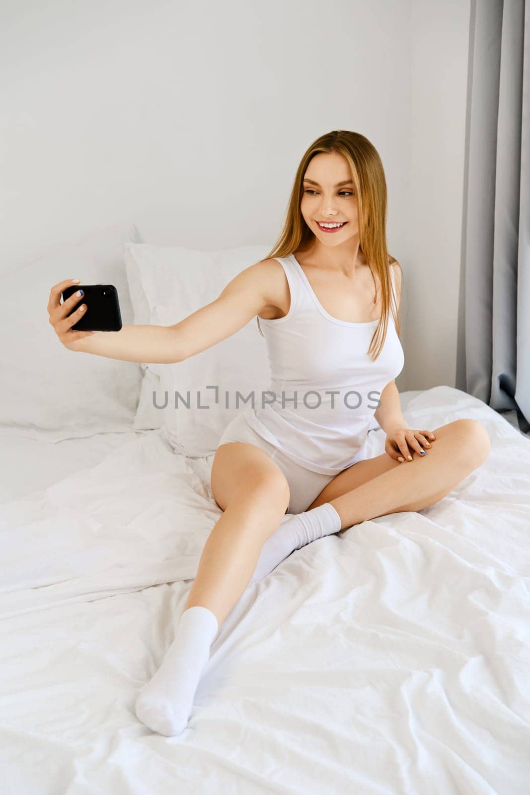 Young woman makes selfie for social network in bed