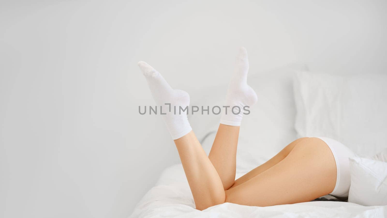 Beautiful female legs in white cotton socks in bed in profile