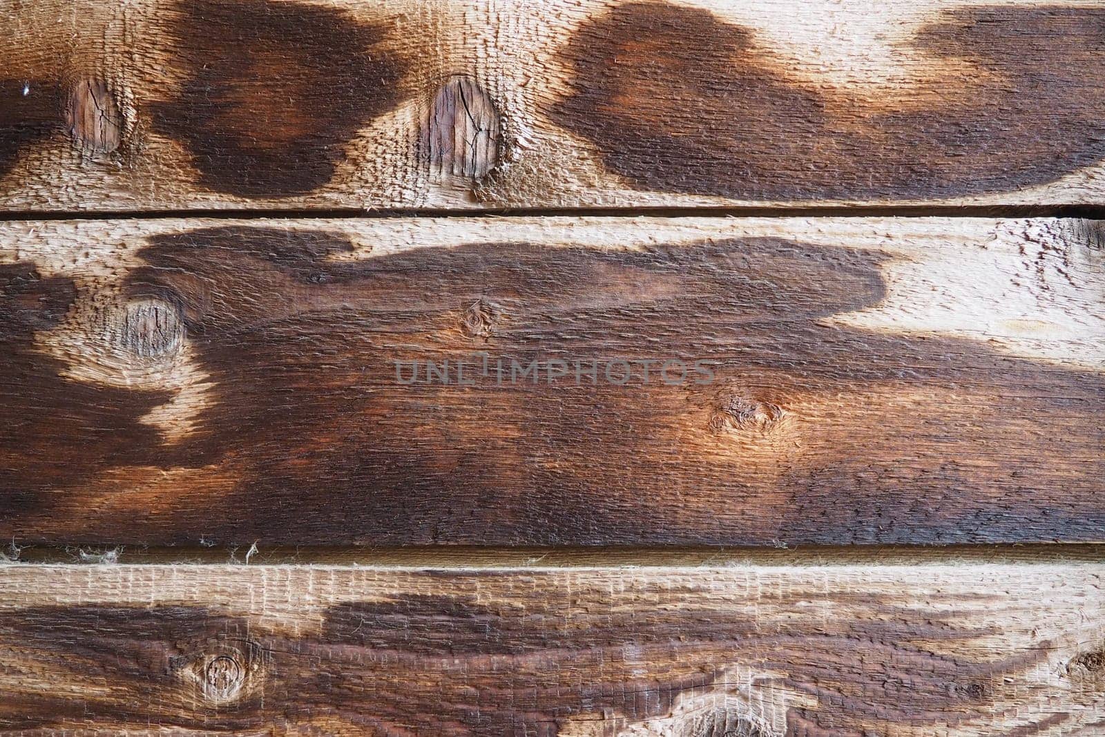 Burnt scorched horizontal boards background. Wooden background close-up with black burnt spots
