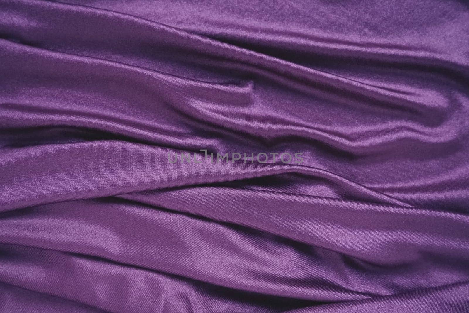 Velour fabric, similar to silk. Textiles in a folds and beautiful waves. Purple, pink, magenta shades on the drapery. Sewing material for evening dresses, furniture upholstery, curtains and interior